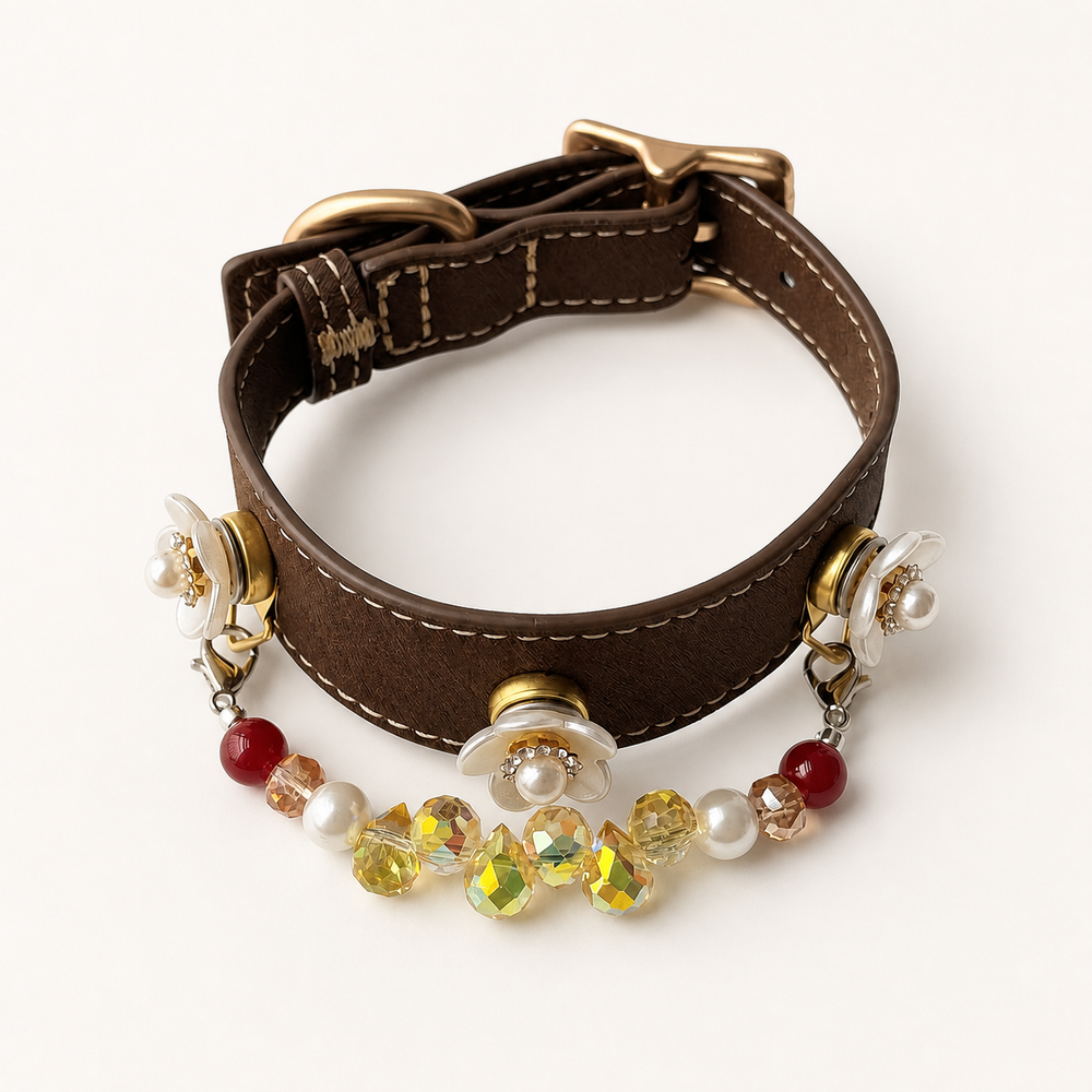 Brown dog collar with three white floral charms and a red, pearl and yellow bead strand