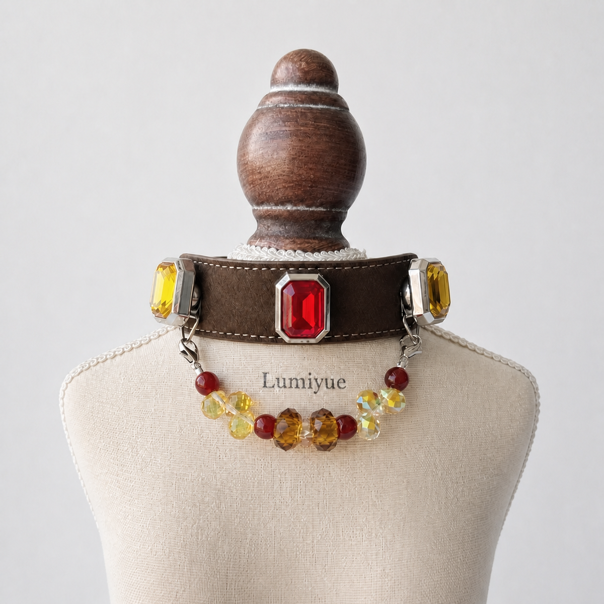 Brown red and yellow charm dog collar displayed on a cream Lumiyue stand