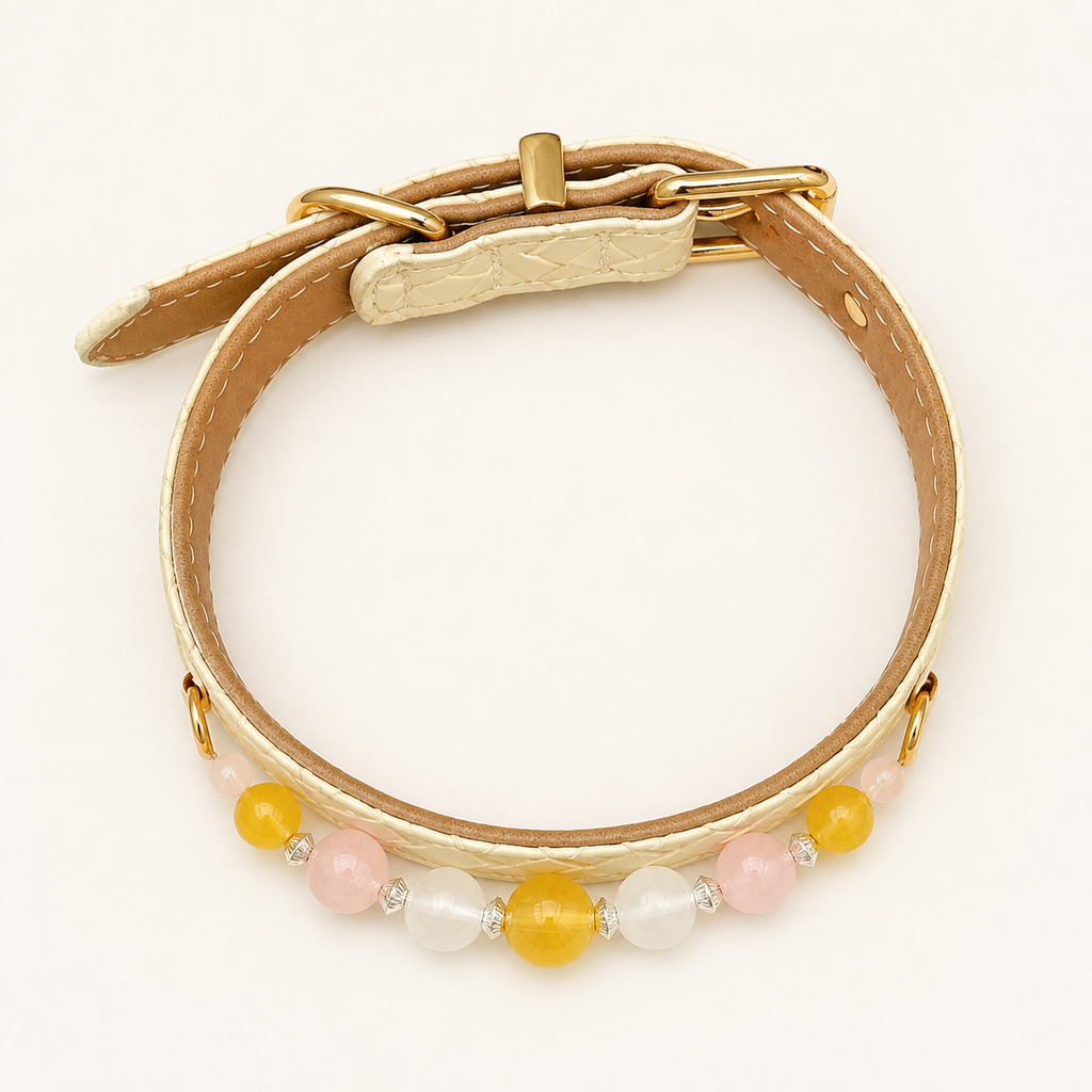 Overhead view of ivory dog collar showing tan lining, gold-tone hardware and nine beads